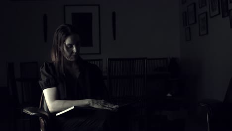 hispanic woman in a moody, dark room looking at a photography portfolio book