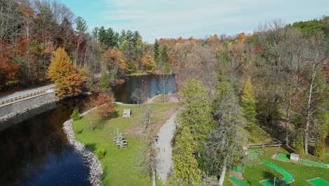 drone flying through a valley with a river flowing through during fall