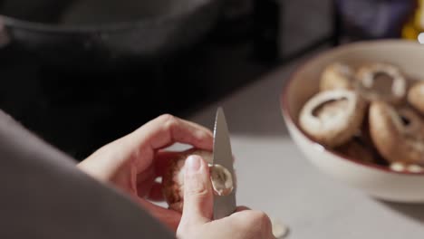 cerca de las manos de la mujer cortando y limpiando setas en la cocina