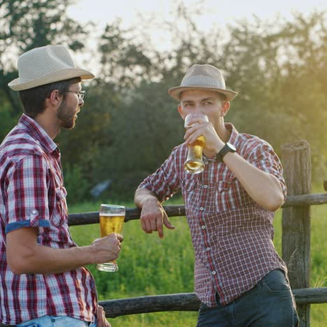 Two-farmers-drink-beer-stand-at-the-fence-of-their-ranch-1