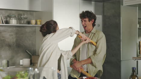 playful couple having fun with baguettes in the kitchen