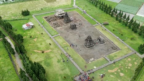 Historical-stone-temple-surrounded-by-rice-fields,-aerial-drone-view