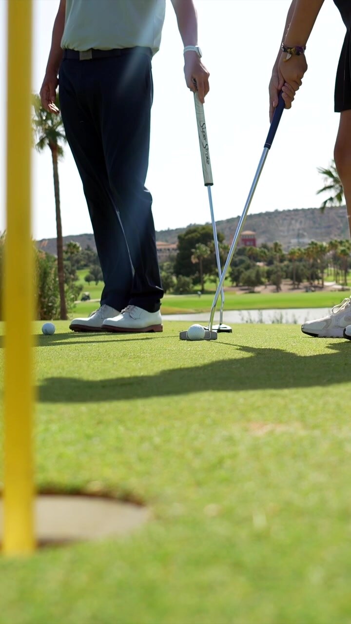 Golfisti che si esercitano nel putting sul green di un campo da golf soleggiato