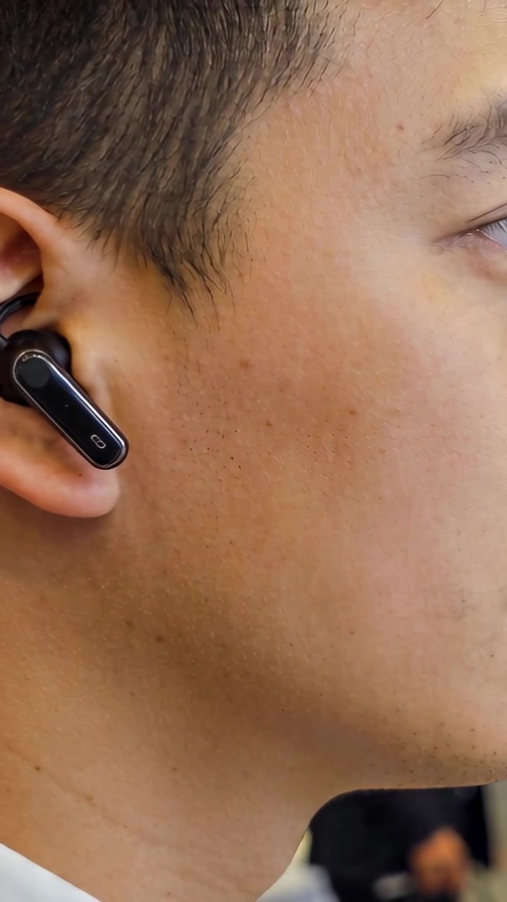 Video verticale: Uomo adulto che ascolta, inclinando la testa per sentire il presentatore allo stand, con auricolare nero.