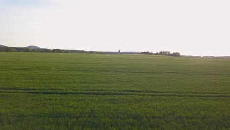 Aerial-wide-angle-shot-of-agricultural-land-with-a-small-church-far-away