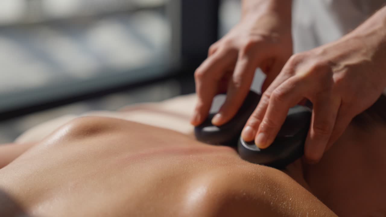 Nærbillede af hot stone massage på en kvindes ryg