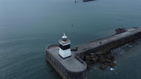 Holyhead-breakwater-lighthouse-longest-concrete-coastal-sea-protection-landmark-aerial-view-birdseye-zoom-out