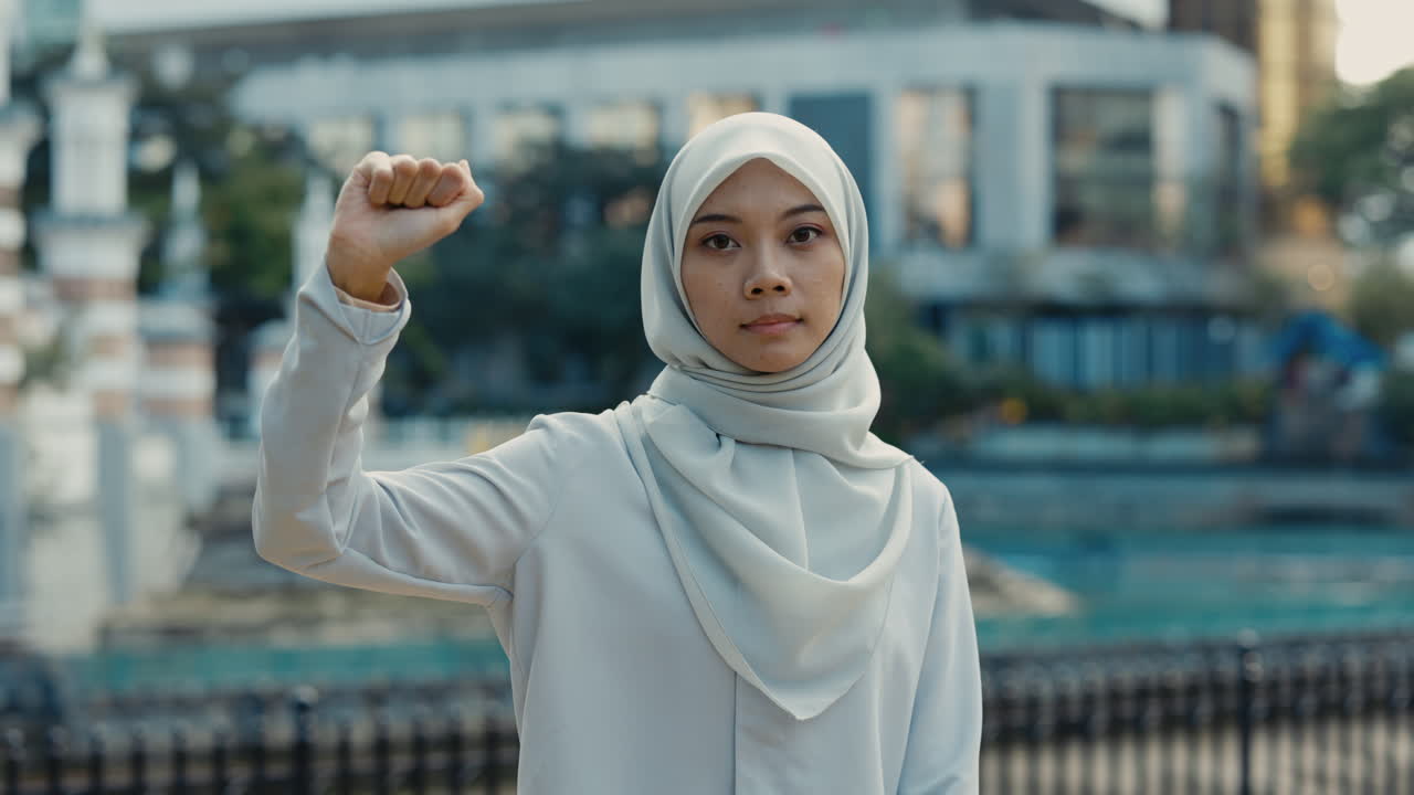 Young Muslim Woman in Hijab Raising Her Fist in an Urban Setting