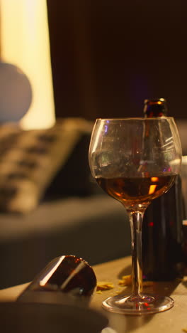 Vertical-Video-Of-Messy-Table-Covered-With-Empty-Wine-Glasses-With-Beer-Bottles-And-Snacks-After-House-Party-2