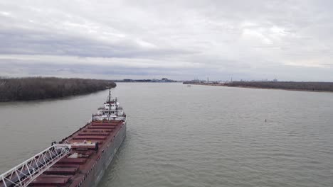 Massive-freighter-vessel-in-industrial-crane-on-Detroit-river,-aerial-fly-over-view