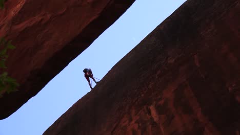 canyoneerer begins rappel with sickle moon visible off his right shoulder