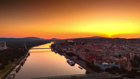 amazing orange sky over the scenery of the old city and river waterscape. drone footage above the danube in bratislava, slovakia at sunset