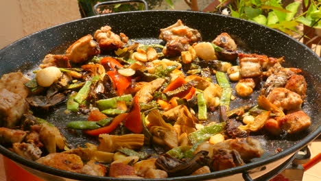 sauteed chicken and vegetables on a shallow pan for paella - typical valencian cuisine