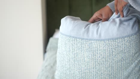 person folding light blue clothes or bedding in a room