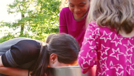 three young girls apple bobbing at a backyard party