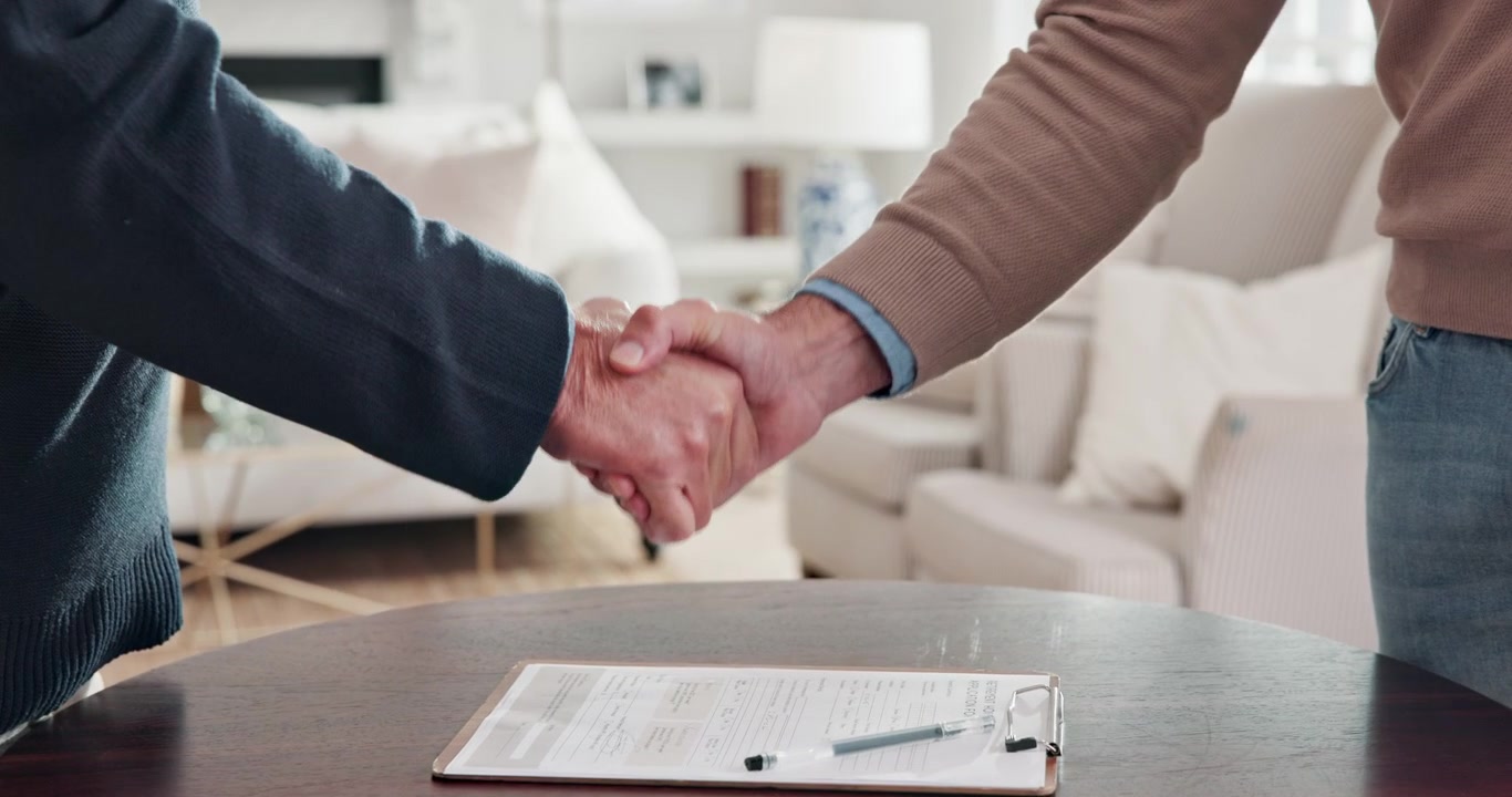 Due uomini che si stringono la mano su un documento firmato