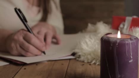 woman writing out christmas greeting cards by candlelight