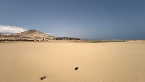 expansive view of the vast sand flats of sotavento beach at low tide, with distant mountains and people walking. fuerteventura, canary islands, spain