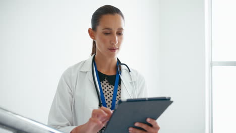 Doctora-Con-Tableta-Digital-Comprobando-Notas-De-Pacientes-En-Las-Escaleras-Del-Hospital