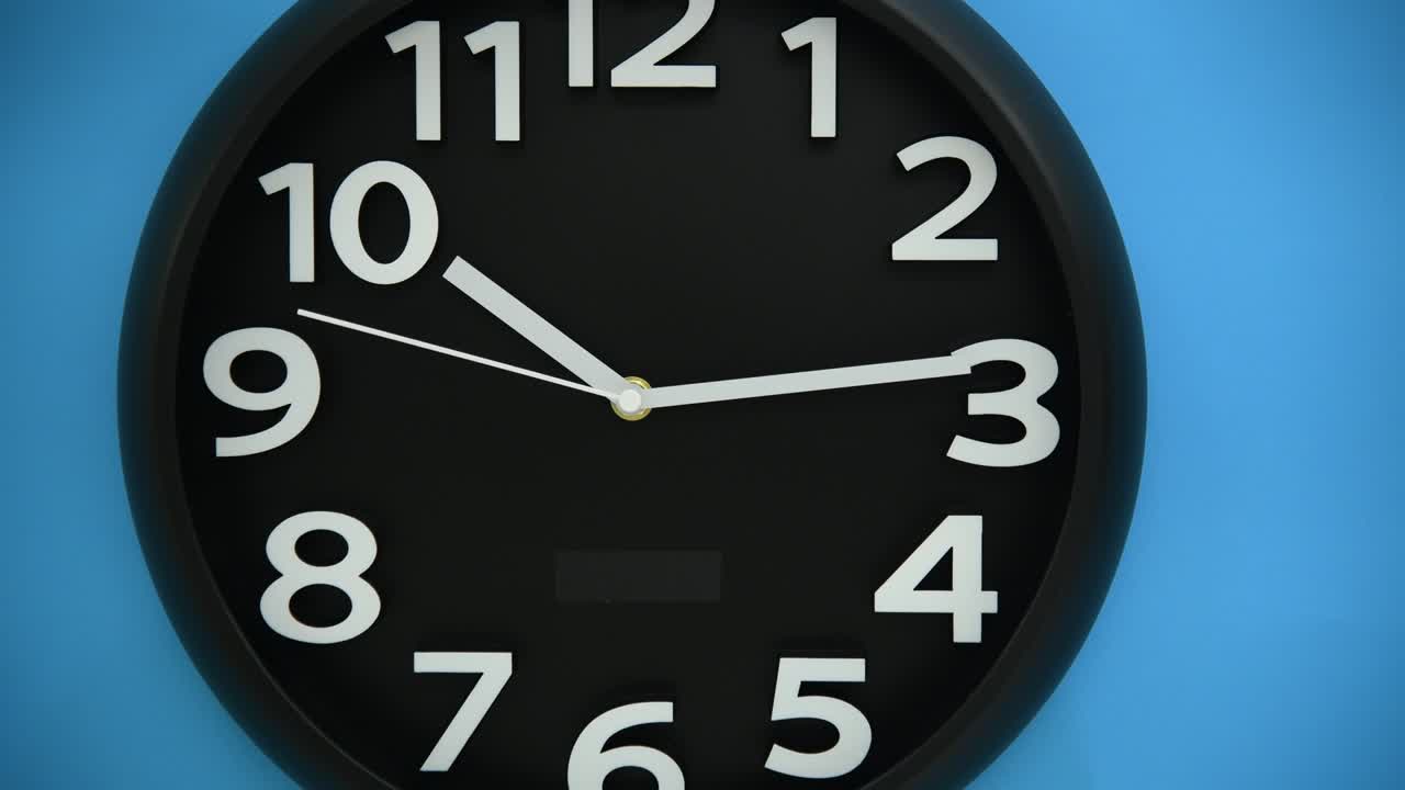 Black wall clock on blue background