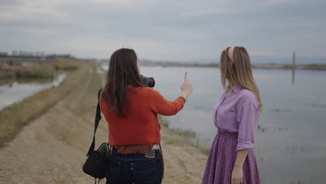 two women taking pictures of each other at a lake