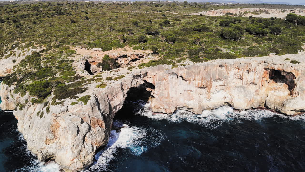 A drone shot panning around to reveal a large sea arch near cala varques in majorca