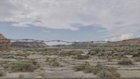 high quality 3d cgi reveal shot rising over a chainlink fence at the area 51 military installation in a desert scene, with a uap ufo emerging from the distant clouds at speed and zooming overhead