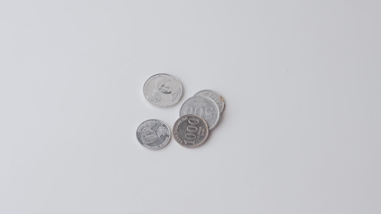 una mano colocando billetes de rupias indonesias en una superficie blanca