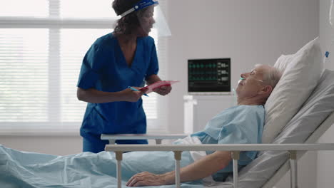 a black female surgeon is talking to an elderly male patient lying on a hospital bed. a female cardiologist infectious disease specialist is talking to a patient in the clinic