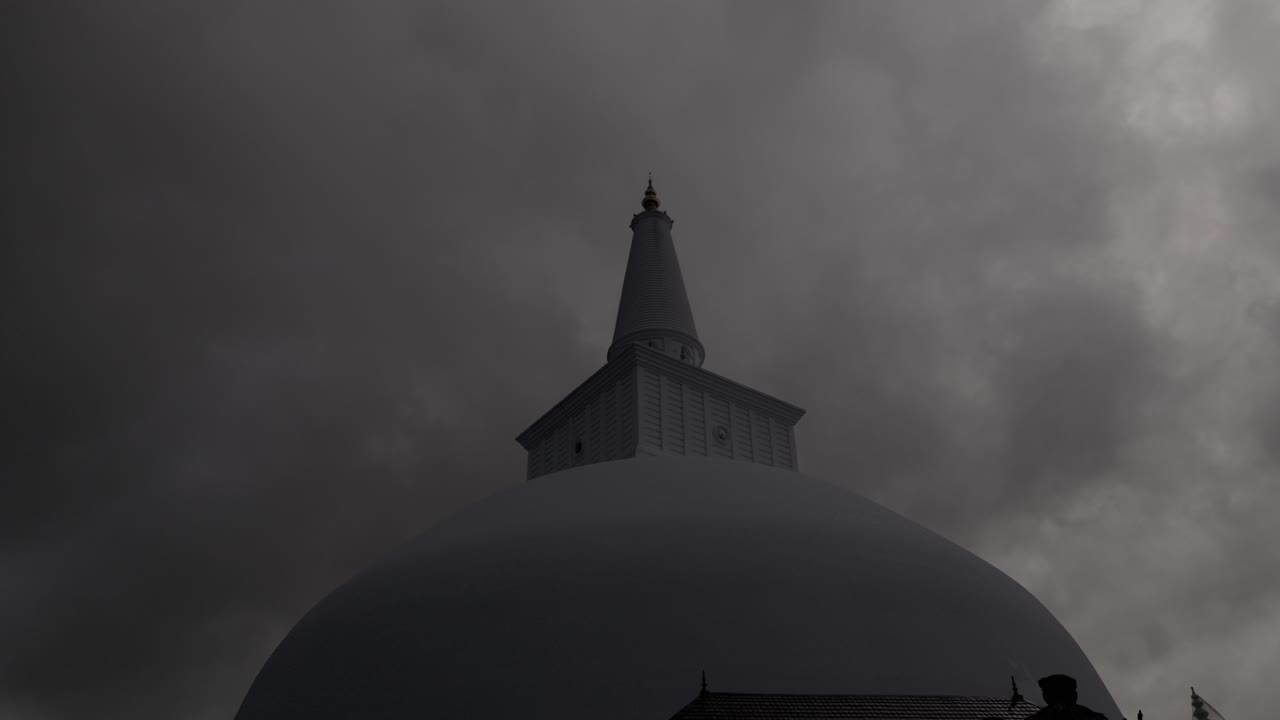 Storm clouds darken the atmosphere around Buddhist stupa, Sri Lanka.