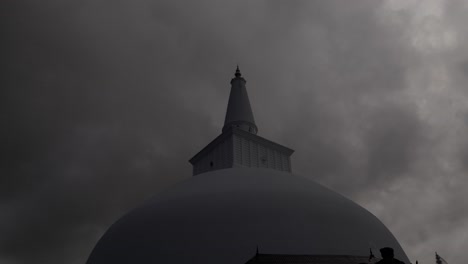 storm clouds darken the atmosphere around buddhist stupa, sri lanka.