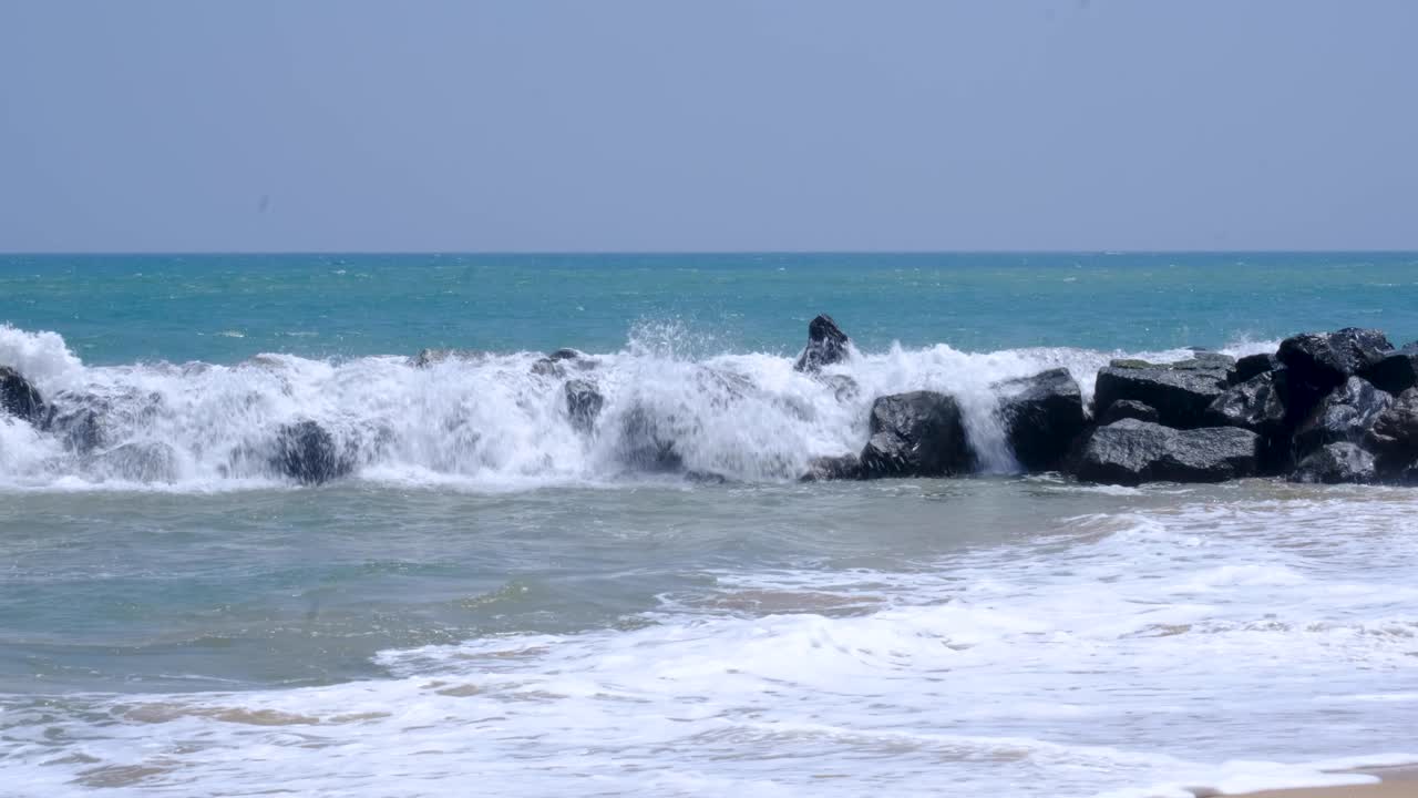 Frothy ocean waves splashing over rocky stone seawall in southern Sri Lanka