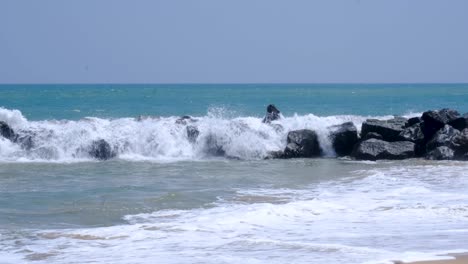 frothy ocean waves splashing over rocky stone seawall in southern sri lanka