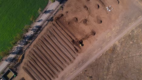 Aerial-rotation-of-yellow-tractor-working-with-compost-mixture-on-a-farm-in-mexico