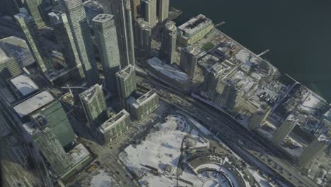 aerial view of downtown toronto with large skyscrapers, snow covered ground and a half frozen lake ontario on a cold winters day