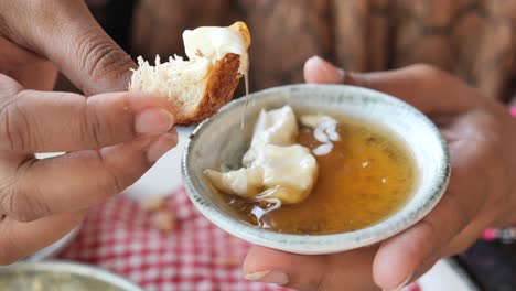 person dipping bread in honey and butter