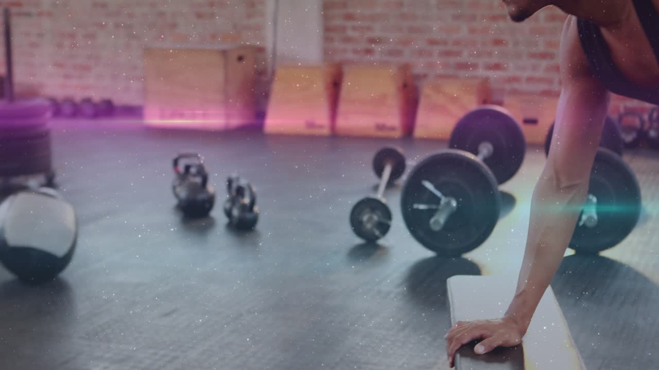 Man entering frame, bracing bench and doing dumbbell rows for fitness, pink-teal streaks across