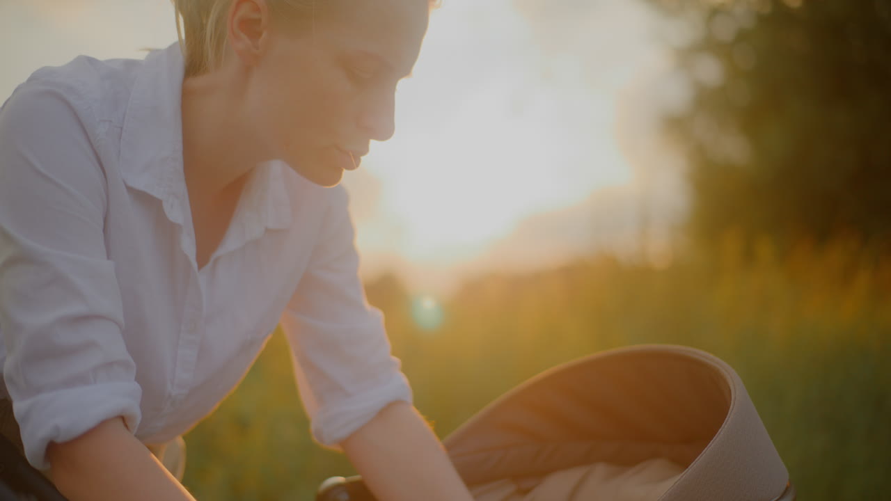 Mother Soothes Baby in Stroller at Sunset