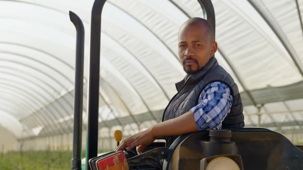 homem sentado em um trator e olhando para a câmera 4k