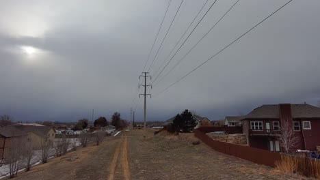 road to sky pan upward as the drone flies toward a dark sky under high voltage power lines.