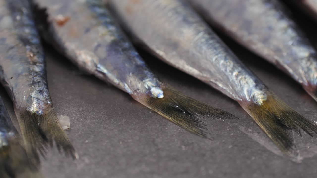 Fresh Sea sardines and Anchovy Fish and Mullus On Display On Ice On Market Store Shop. Seafood Fish Background, close up stand of small salty white fish.