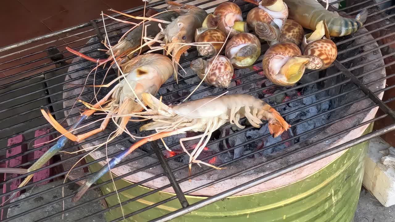새우와 조개가 석탄 불 위에서 요리되고 있습니다.