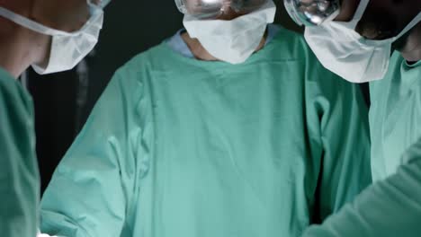 diverse surgeons with face masks during surgery in operating room in slow motion