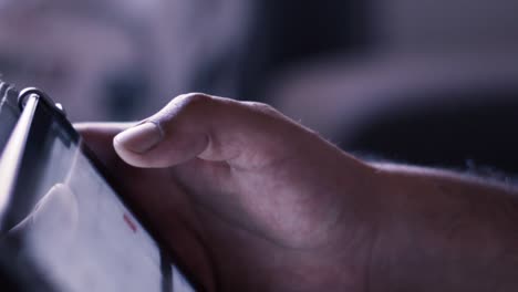 shooted in slow motion showing man's hands browsing social media or playing with a mobile tablet at evening (dark space)