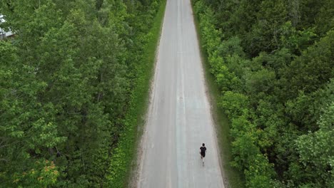 a runner on the road between green trees