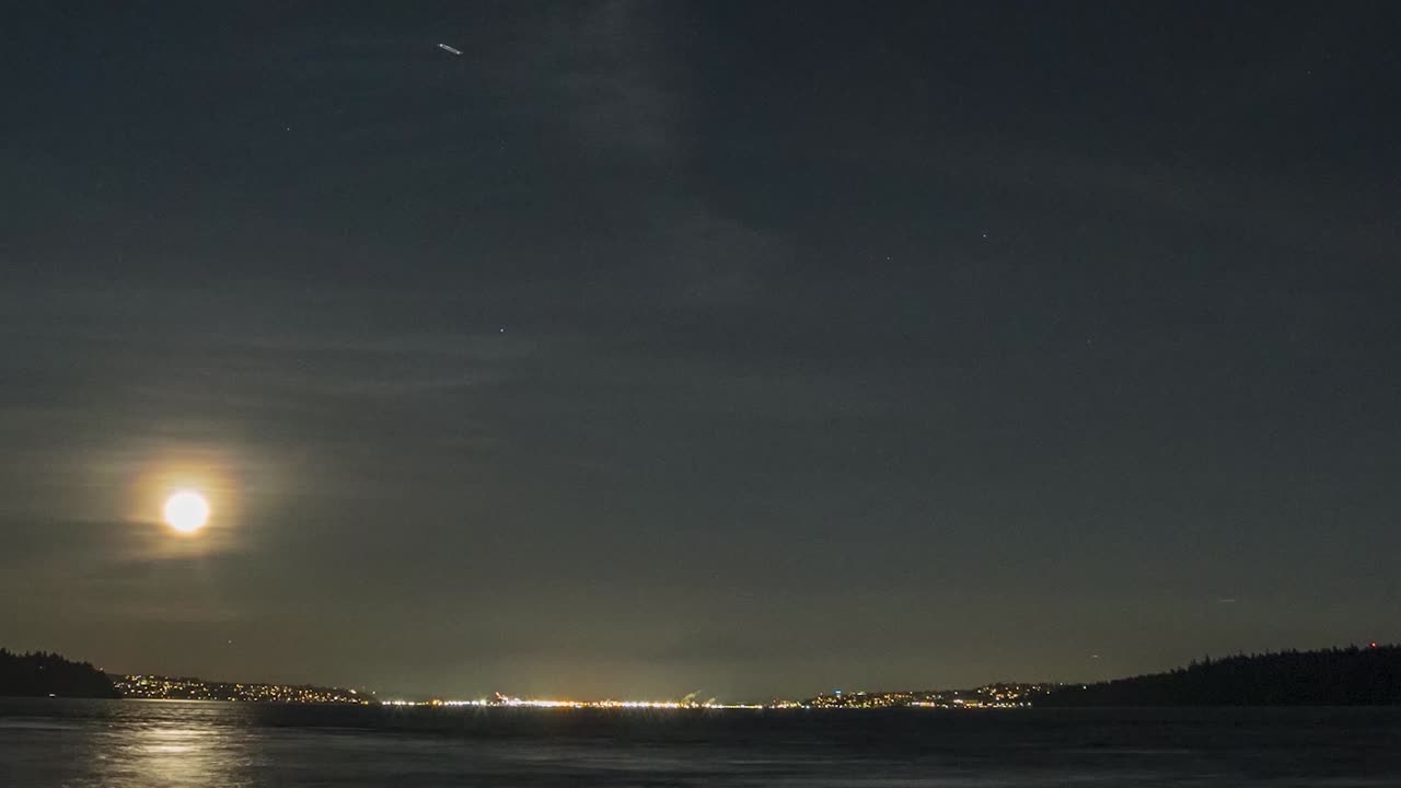 Hyperlapse of golden full moon rising above shimmering black waters of Puget Sound Washington