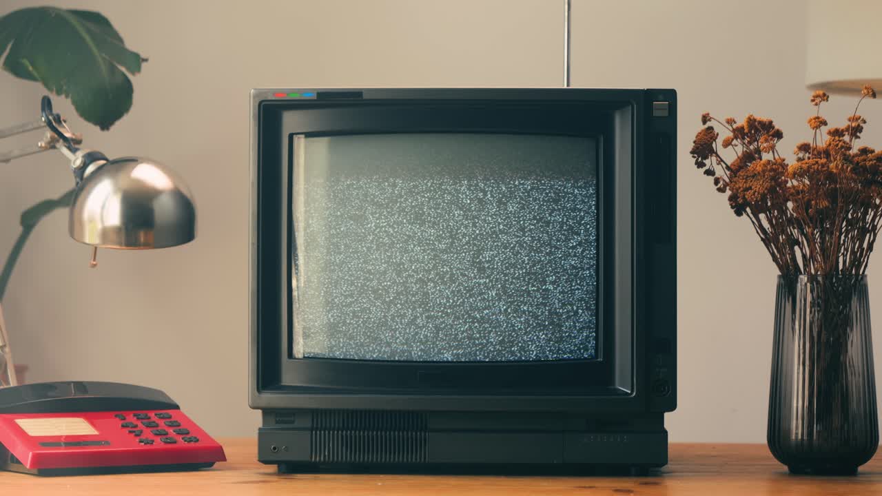 TV retrò, televisione vintage. In un'ambientazione nostalgica, un televisore retrò mostra grana sullo schermo, dispositivo per una spaventosa notte di Halloween, ottimo per chroma key e green screen. Filmato 4K di alta qualità.