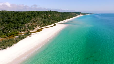 Vista-Aérea-De-La-Isla-Fraser,-La-Hermosa-Playa-Y-El-Agua-Tonificada-Se-Está-Revelando-Con-Un-Dron-Lento-En-Un-Día-Soleado