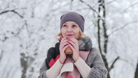 a woman warms up with a hot ay in a winter park