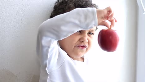 niño mirando manzana sobre fondo blanco material de archivo de vídeo